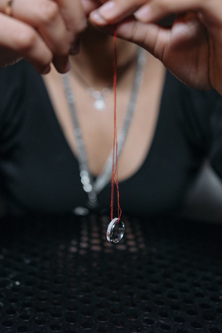 Mystical close-up of a crystal hanging from a red string, suggesting spiritualism.